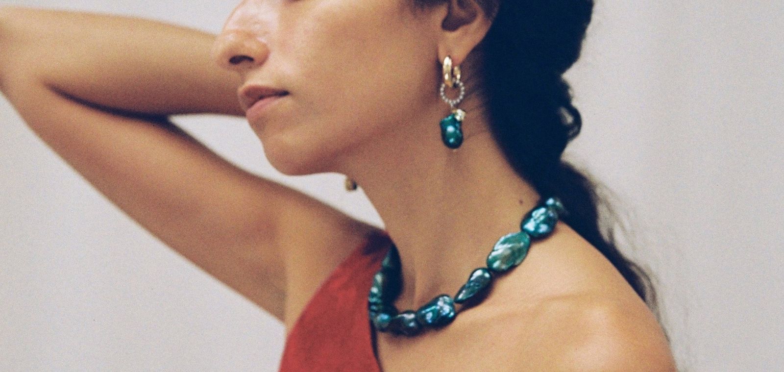 Collier de perles baroques bleu-vert et créole portés de profil